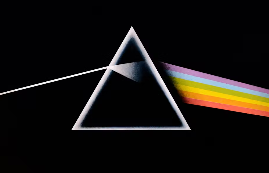 A white beam of light enters a transparent triangle, which disperses the light into a rainbow spectrum against a black background.