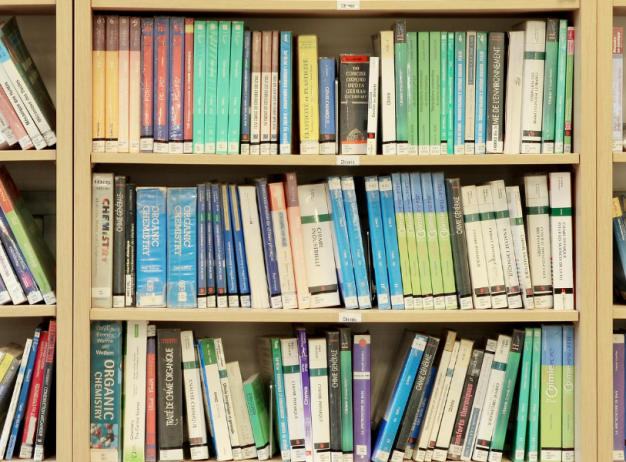 Bookshelves filled with a variety of neatly arranged books, mainly academic and reference, showcasing diverse colors and sizes, creating a scholarly tone.